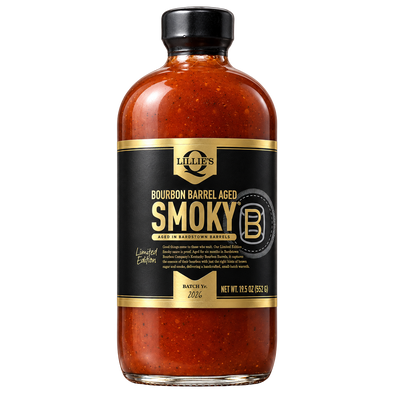 A bottle of Lillies Bourbon Barrel Aged Smoky BBQ sauce, featuring a black label with gold lettering and a black cap, set against a plain white background.